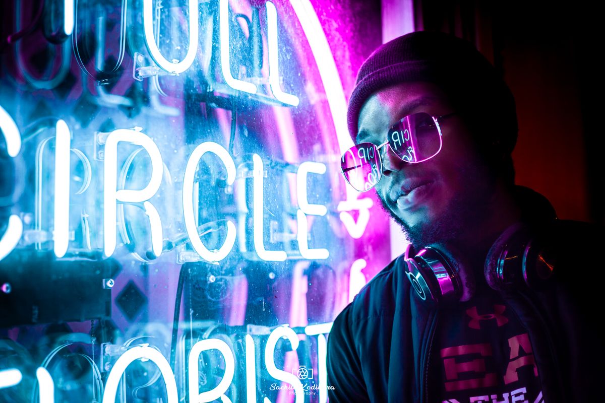 Man in a dark jacket and glasses under neon light