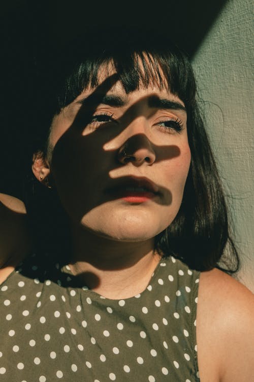 Woman in White and Green Polka Dot Top and Shadow of Palm on Her Face