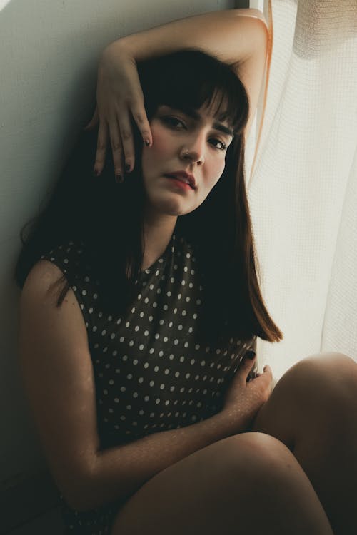 Woman in Polka Dot Sleeveless Dress Holding Hand on Head