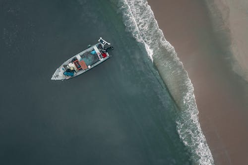 Aerial view of small modern motorboat moored on sandy seacoast near tranquil sea