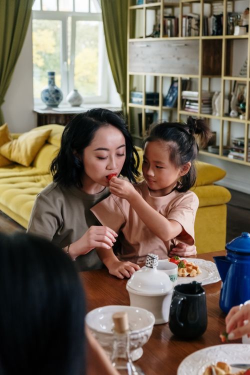 Free Heartwarming scene of mother and daughter enjoying breakfast together at home. Stock Photo