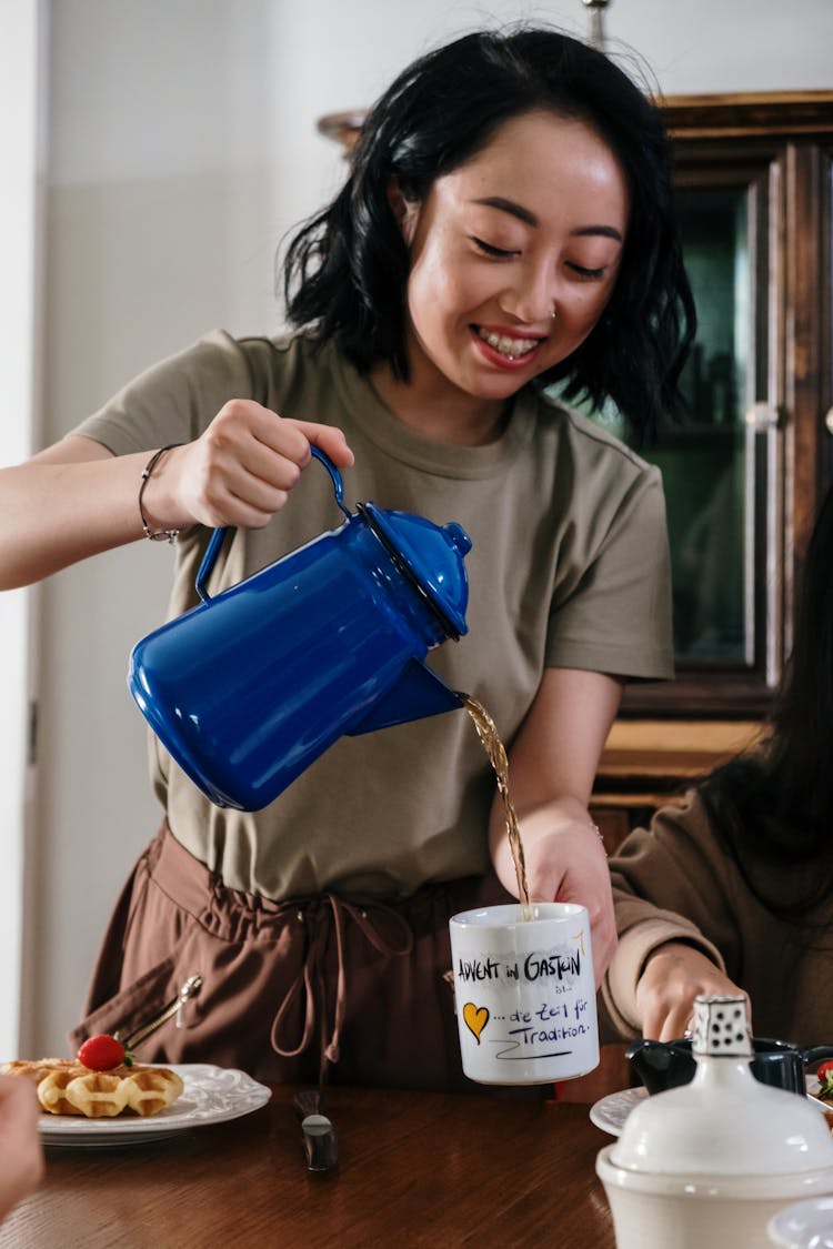 A Woman Pouring Tea In A Cup