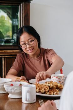 一个十几岁的女孩正在家里享用华夫饼和咖啡，享受舒适的早餐