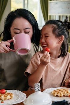 Mother and daughter share a joyful breakfast with waffles and strawberries.