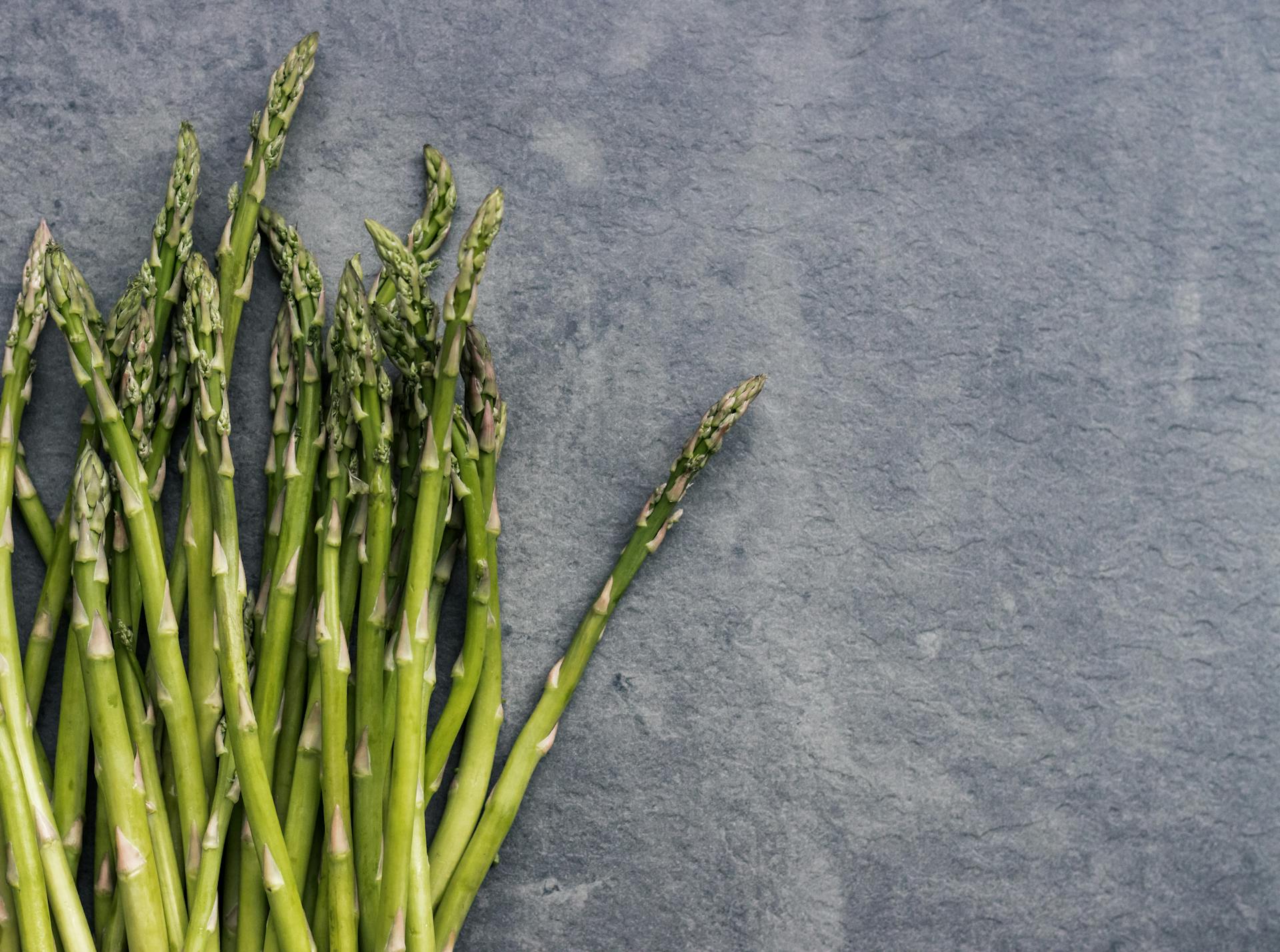 Close-up of fresh asparagus stalks on a textured slate background, perfect for health and food themes.