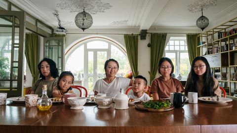 A diverse family enjoying dinner together in a cozy living room setting.