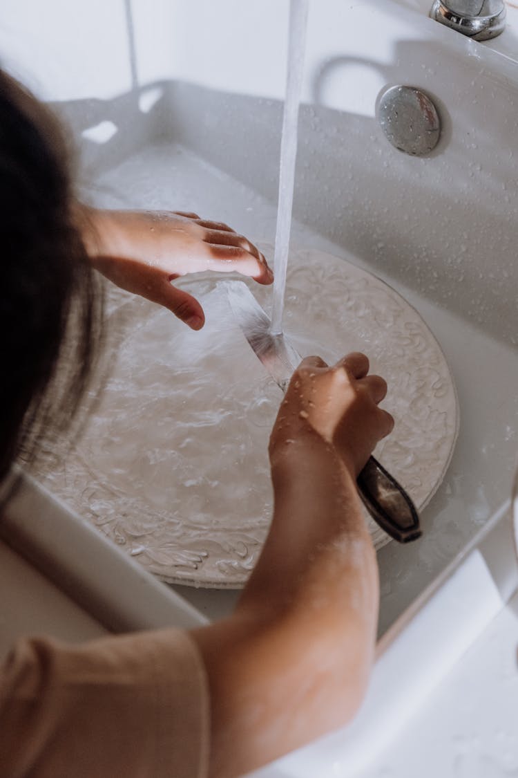 Child Cleaning A Plate On Kitchen Sink 