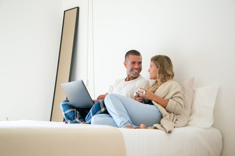 Man And Woman Sitting On White Bed