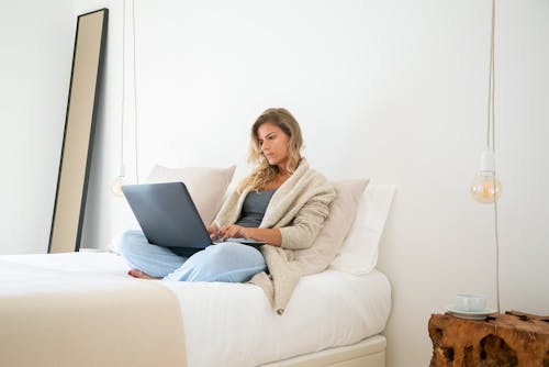 Woman Using a Laptop on the Bed