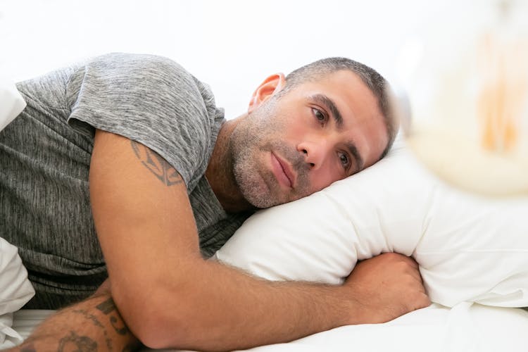 Close-Up Shot Of A Man In Gray Shirt Lying On Bed