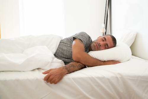 Free Man in Gray Shirt Lying on the Bed Stock Photo