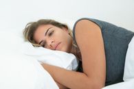 年轻女子枕着白色枕头休息，描绘出室内的平静与放松