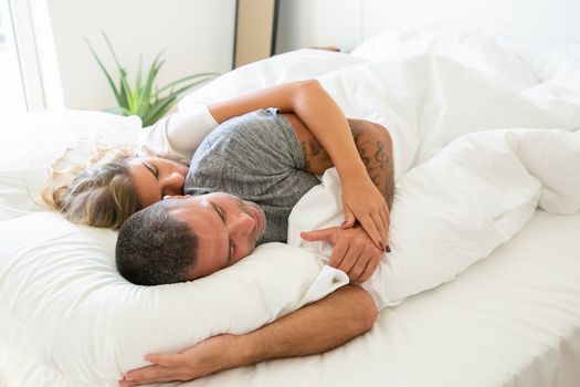 一对夫妇在阳光明媚的舒适卧室里休息时，深情地拥抱在一起