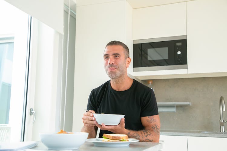 Man In Black Shirt Eating His Breakfast