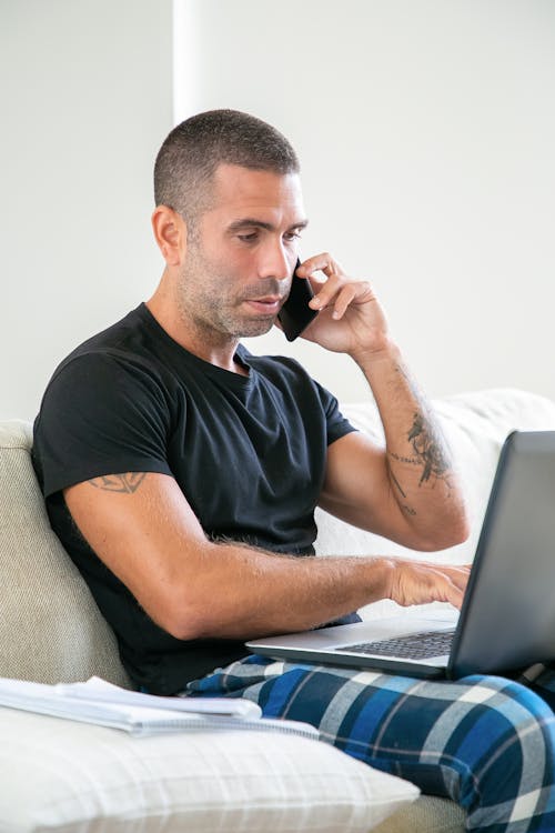 Man Talking on the Phone and Using a Laptop Computer