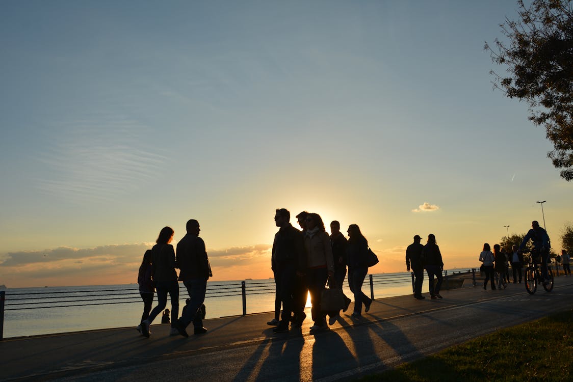 Силуэт людей на берегу моря во время заката