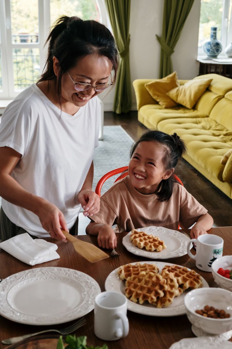 Mother serving waffles to her daughter at the table
