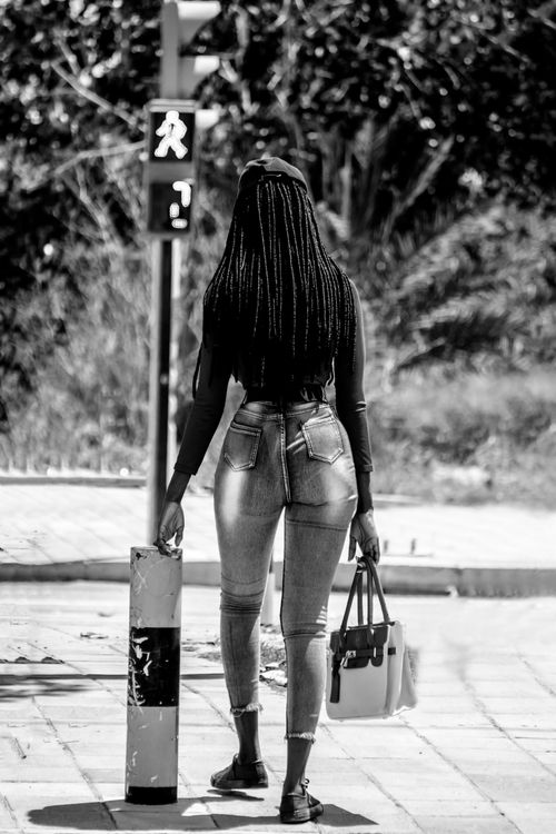 Free Back view of anonymous African American female with Afro braids near traffic light on street in summer Stock Photo