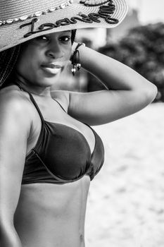 Black and white of African American male in swimwear looking at camera on blurred background of sandy shore