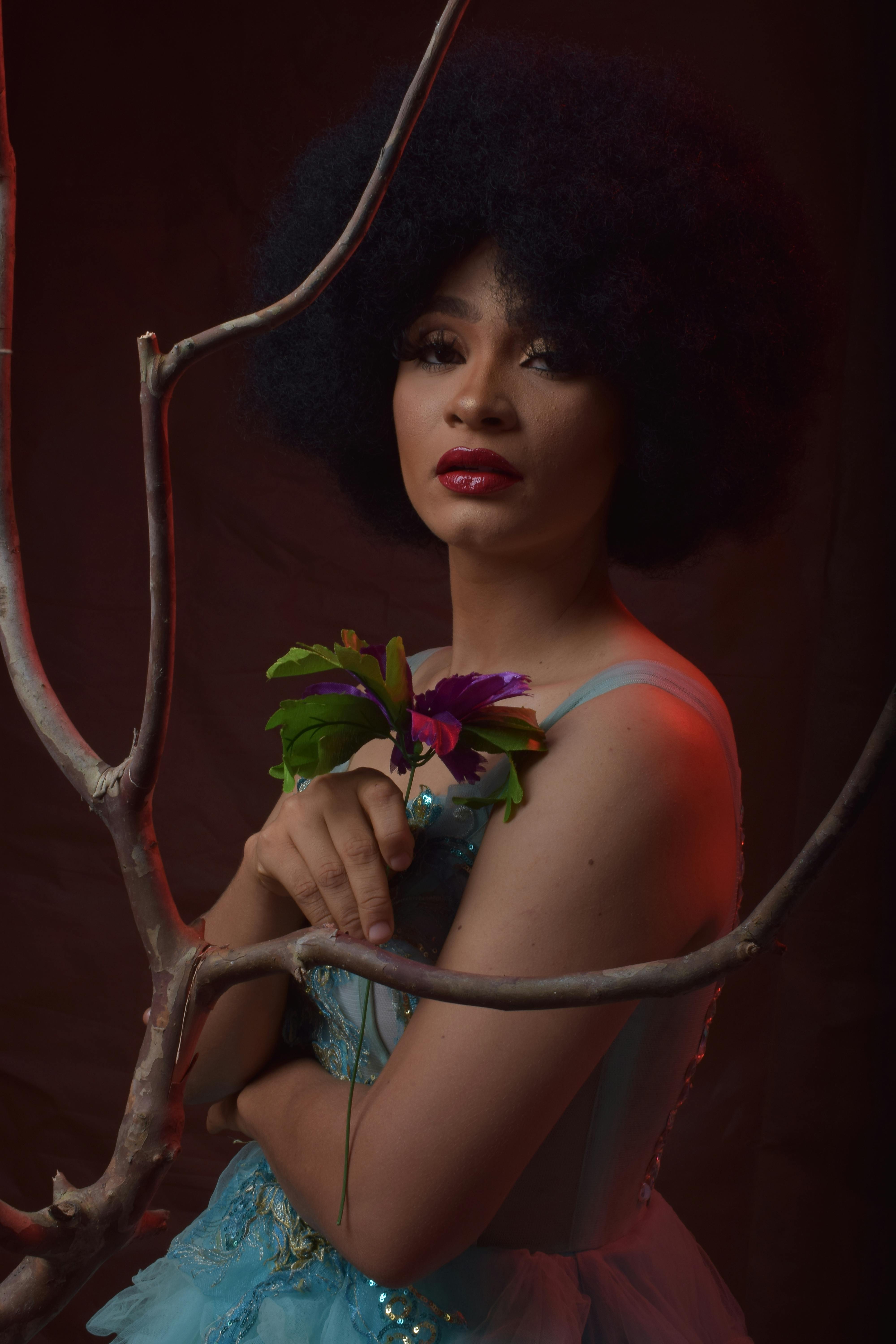 person with afro hair holding a flower