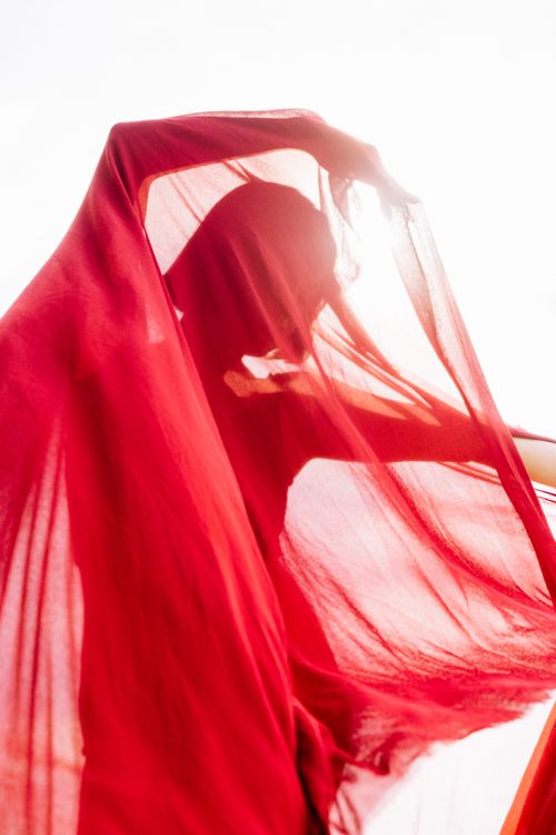 Free Captivating silhouette of a dancer enveloped in flowing red fabric, exuding grace and mystery. Stock Photo
