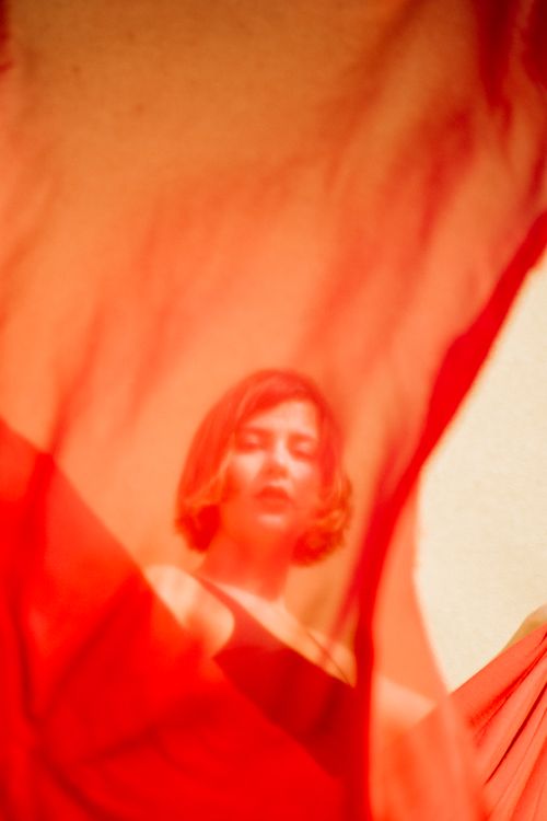 Free Artistic shot of a woman with short hair viewed through flowing red fabric. Stock Photo
