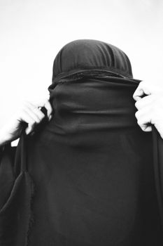 一个女人调整面纱的特写镜头，象征着信仰与文化