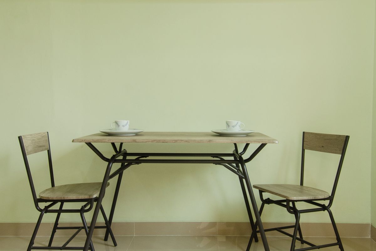 Colț de sufragerie minimalist, cu o masă din lemn și două scaune simple din lemn
