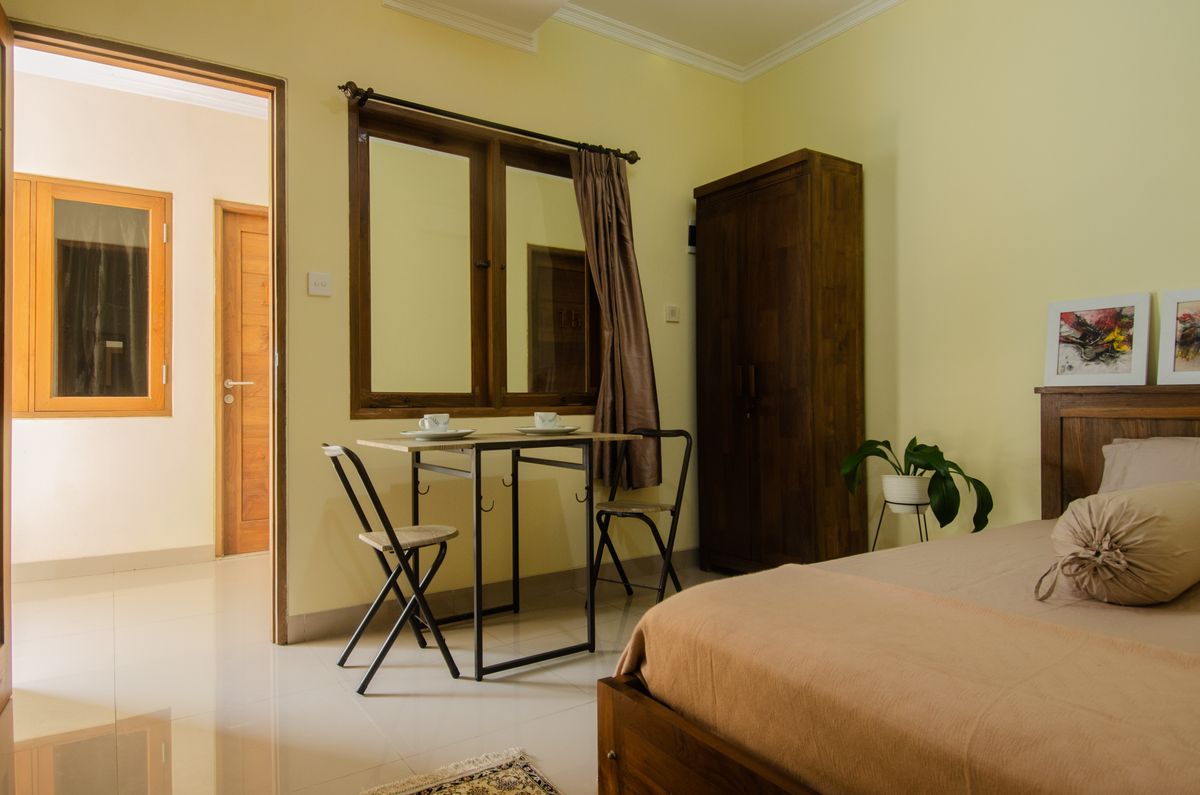 Cameră simplă și curată, cu pat, masă și scaune, fără decorațiuni sau lux
