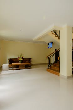 A spacious and modern lobby featuring a wooden bench, TV screen, and minimalist decor.