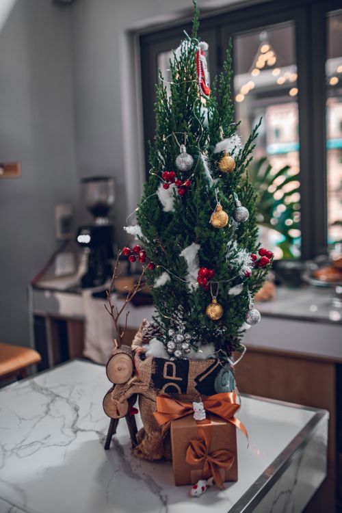Free Festive Christmas tree with ornaments and gift on marble table indoors. Stock Photo