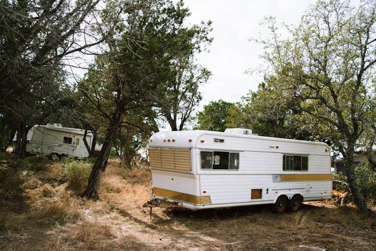 White And Brown Rv Trailer Near Green Trees