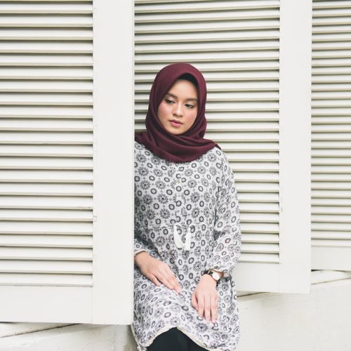 Free A young woman in a patterned dress and hijab poses gracefully by shutters in Jakarta. Stock Photo