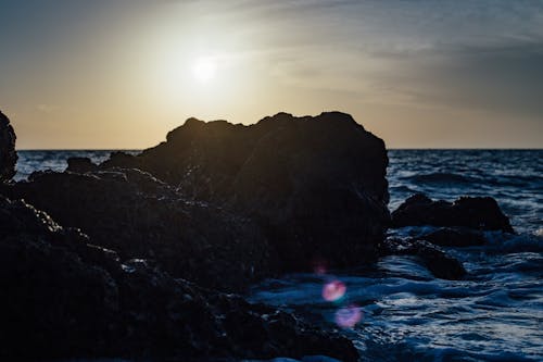 無料 日没時の海側の黒い石 写真素材