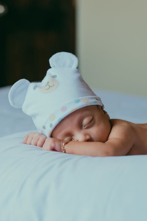 Bébé En Chapeau Imprimé Ours Blanc Et Bleu Allongé Sur Un Textile Blanc