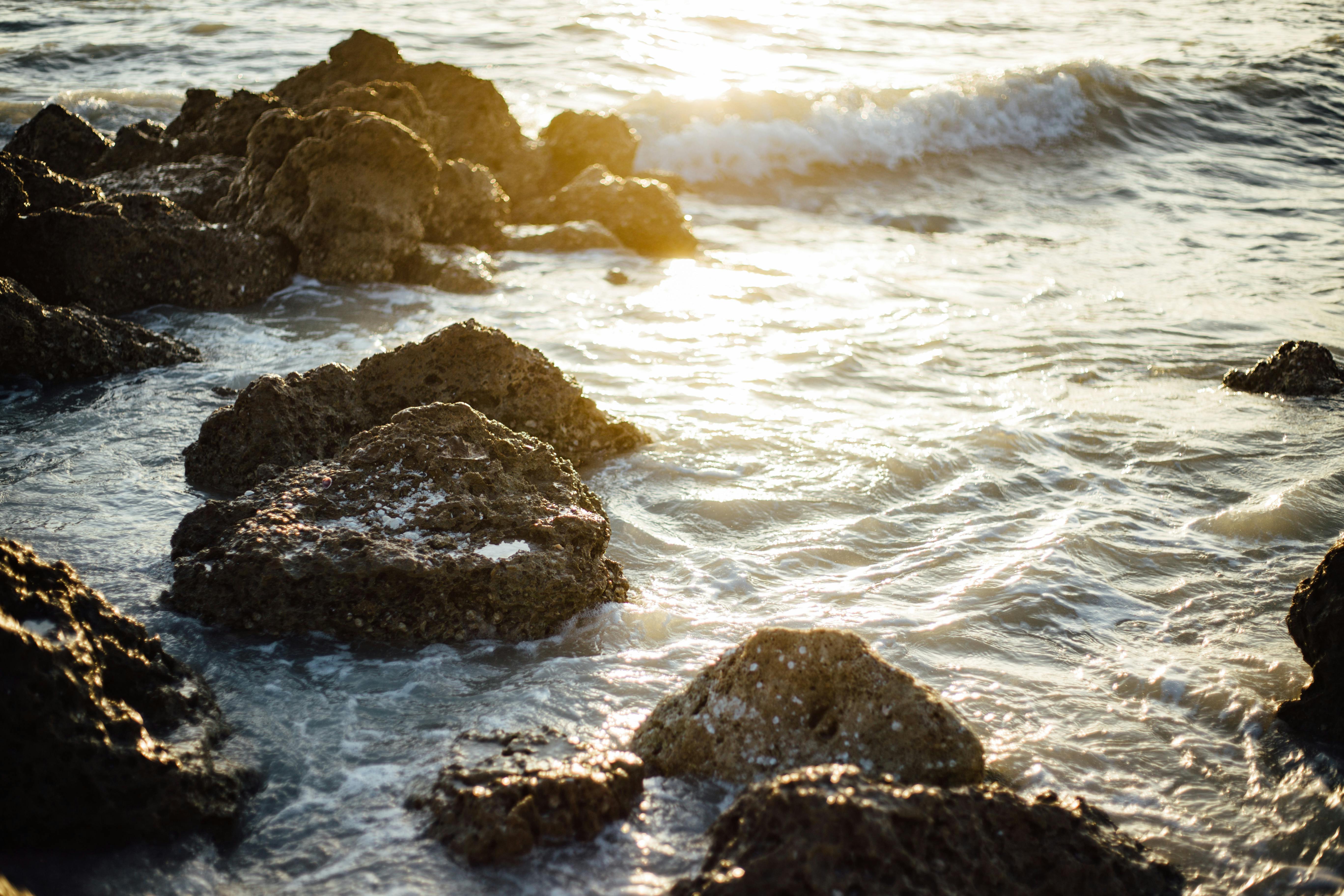 在温暖的阳光下，平静的海浪轻轻拍打着崎岖的岩石海岸线