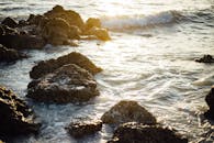 在温暖的阳光下，平静的海浪轻轻拍打着崎岖的岩石海岸线