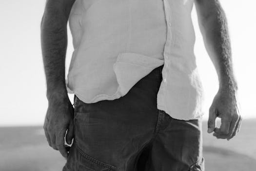 Black and white image showing a man's torso and hands in a serene outdoor setting.