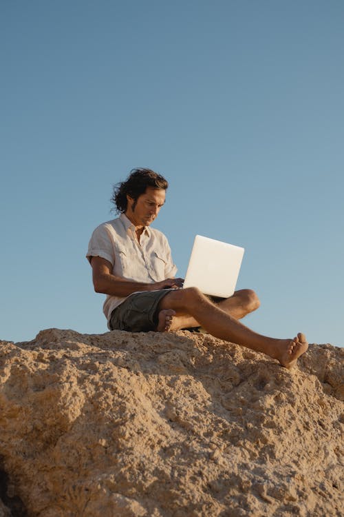 Man in White Button Up Shirt Sitting on a Rock