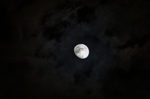 Free Bright white glimmering majestic moon with gray craters in dark sky with clouds Stock Photo