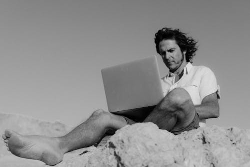 Man in White Polo Shirt Using a Laptop