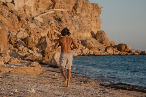 Free Topless Man Running on Shore Stock Photo