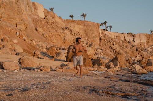 Shirtless Person Running on Shore