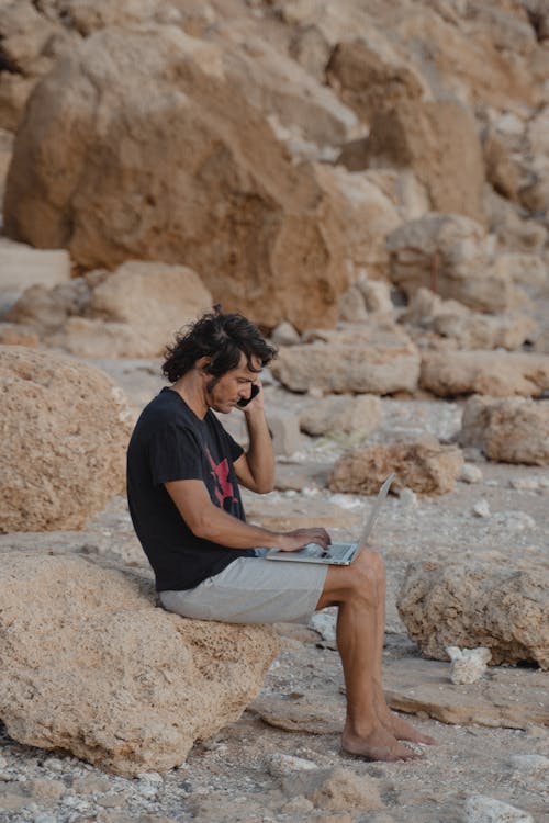 Free Man in Black T-shirt Sitting on Rock Stock Photo