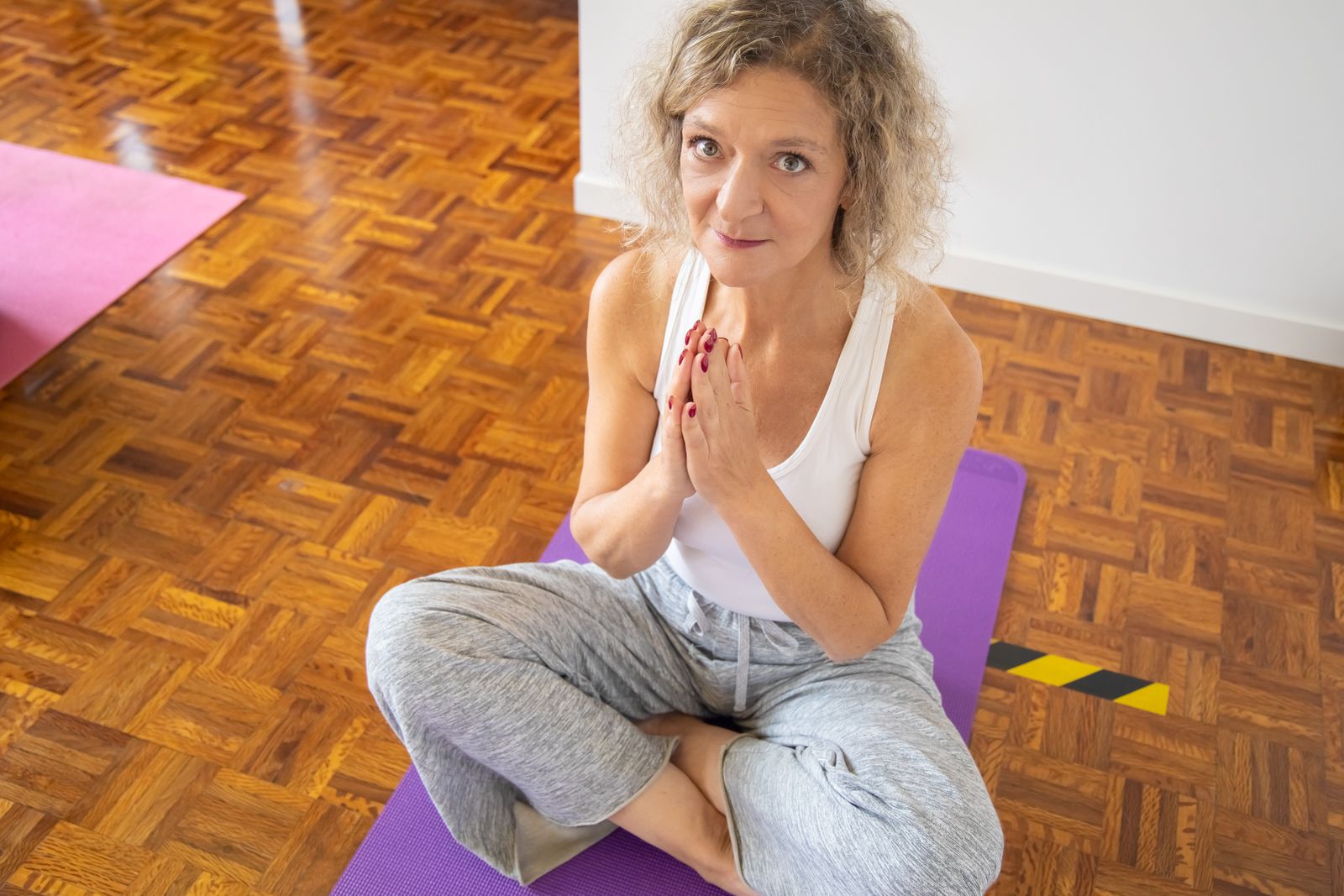 Elderly woman meditating calmly on a yoga mat indoors