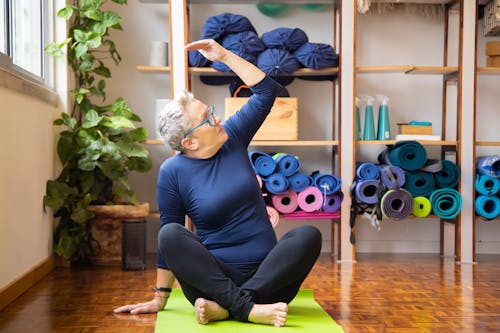 Free Elderly Woman Sitting on Yoga Mat While Exercising Stock Photo