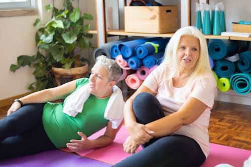 Vrouw In Wit Overhemd En Zwarte Broek Zittend Op Paarse Yogamat