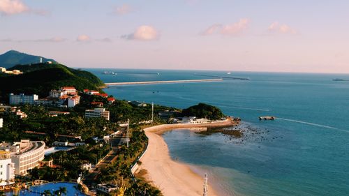 Free Aerial view of a vibrant coastal cityscape with beach and sea under a bright blue sky. Stock Photo
