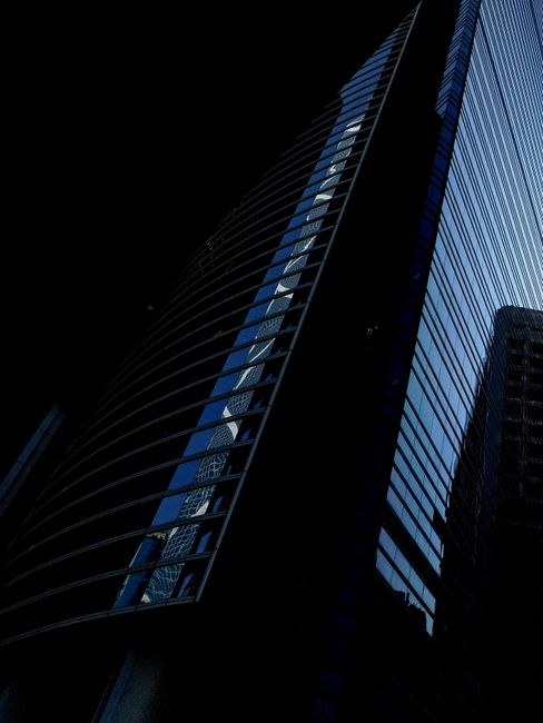 From below exterior of contemporary high rise building with glass mirrored windows located in city district at night