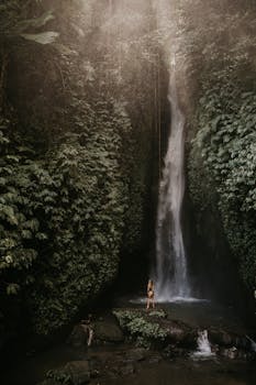 Explore the serene beauty of a towering waterfall surrounded by lush greenery in Bali's vibrant jungle.